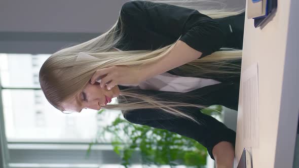 Trendy Business Woman Watching Laptop and Speaking on Phone. Stylish Young Blond Woman Working in