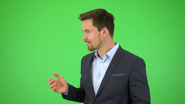 An Amazed Businessman Smiles and Points in Fascination at Objects Floating Around Him - Green Screen