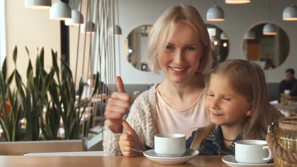 Mother and Daughter Shows Their Thumbs Up at the Cafe