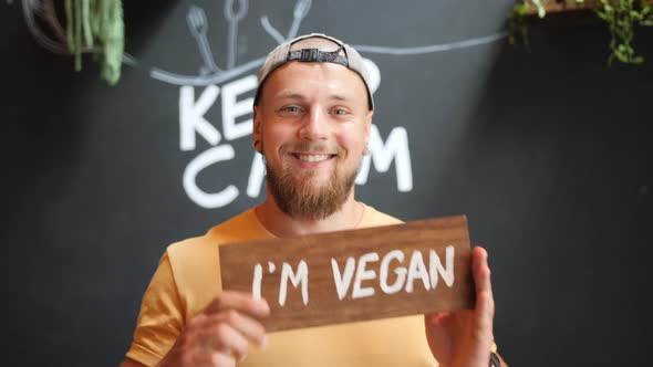 Young Bearded Man Holding Wooden I Am Vegan Sign