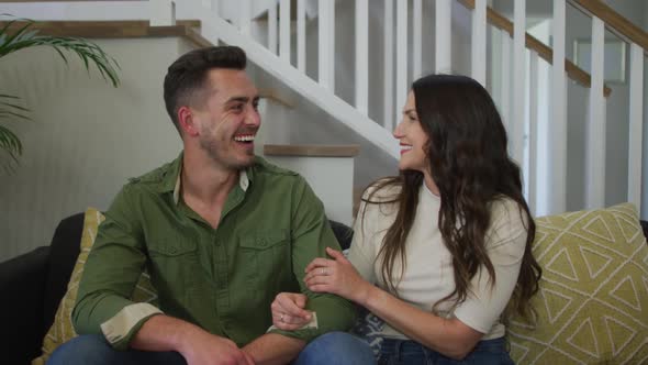 Portrait of caucasian couple sitting on sofa and smiling