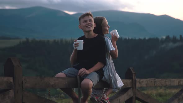 Boy with Mug Speaking with Sister in Evening