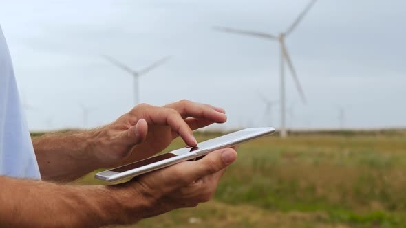 An Energy Engineer Checks Wind Turbines Using a Tablet. Engineer's Hands with a Tablet Close-up. A