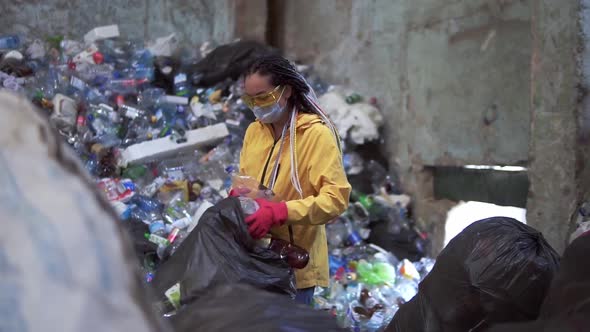 Stylish Woman in Yellow Jacket Protective Glasses and Gloves Sorting Plastic Bottles From Black Bags