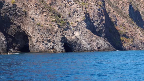 Lipari Island, Mountain with Caves in Mediterranean Sea. Summer Sunny Day, Blue Sky. Rippling Blue