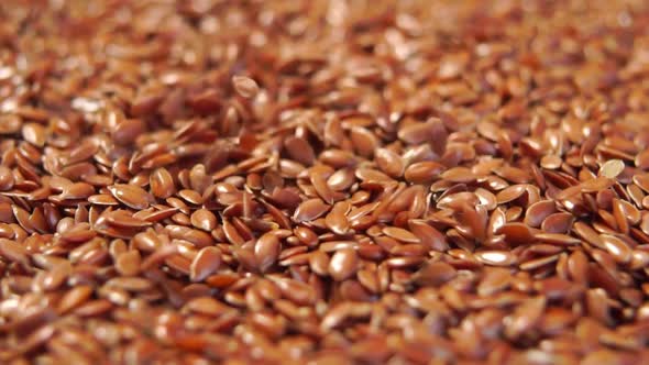 Flax seeds heap close up. Falling brown linseeds in slow motion. Macro