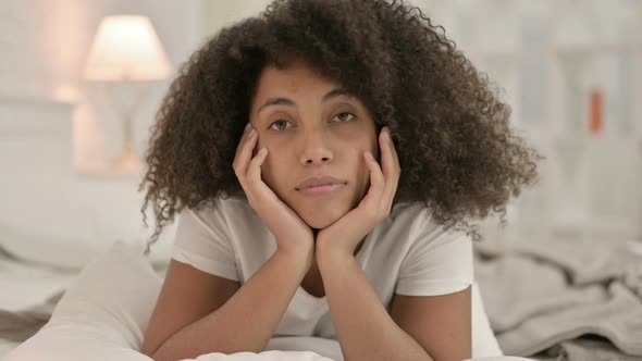 Portrait of Young African Woman Laying in Bed Looking at Camera