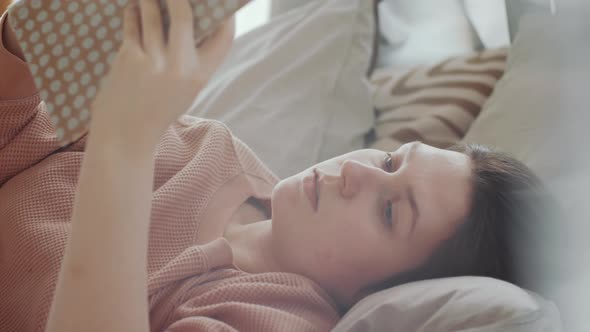 Young Woman Lying on Bed and Reading a Book