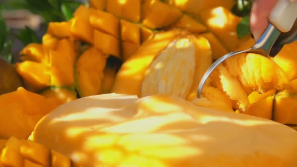 Closeup of the Spoon Slowly Scooping Frozen Mango Icecream Gelato Outdoors