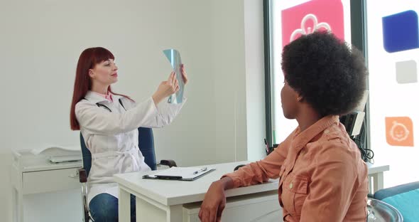 Young Female Doctor Checking Xray of Lungs Advising Patient with Positive