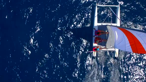 Aerial drone view of a man and woman sailing on a boat to a tropical island.