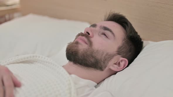 Worried Young Man Trying To Sleep in Bed 