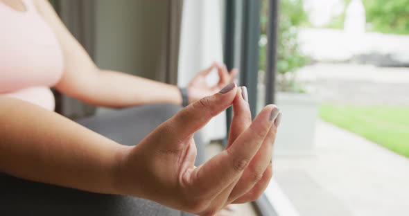 Video of hands of plus size african american woman exercising at home, practicing yoga