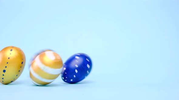 Easter Eggs are Rolling Knocking Each Other on Blue Table