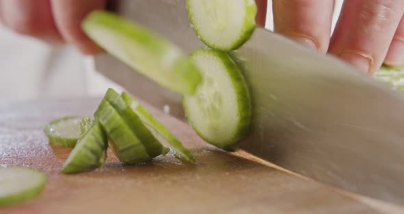 Macro shot of a large chef knife slicing a cucumber