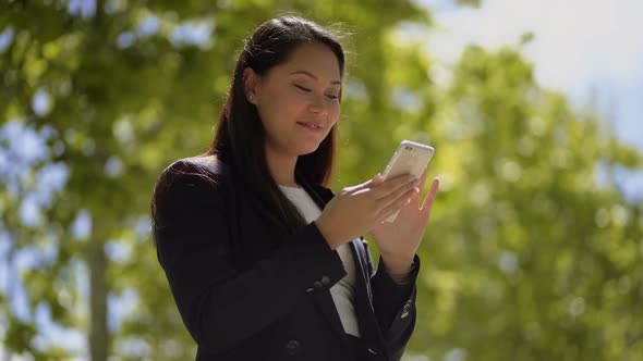 Smiling Young Woman Using Smartphone Outdoor