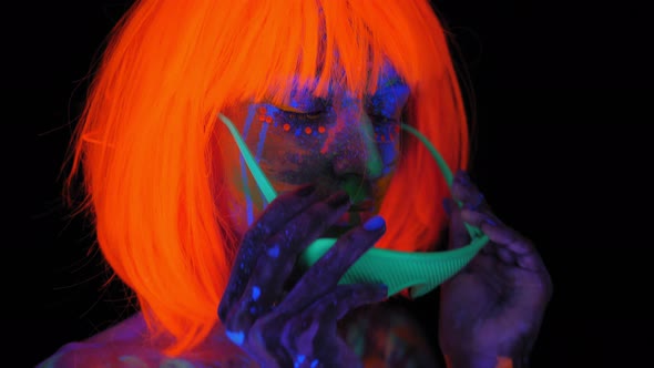A Woman with UV Patterns on Her Body in an Orange Wig Puts on Green Glasses