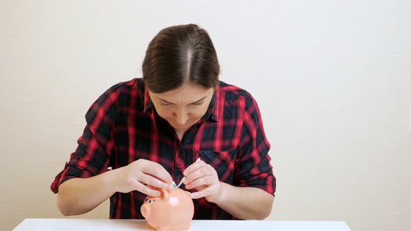 Sly Young Woman Pulls Dollar Banknote Out of Piggy Bank Slot