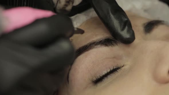 Microblading Procedure. Master Cosmetologist Draws and Notes with Eyebrow Pencil the Customer for