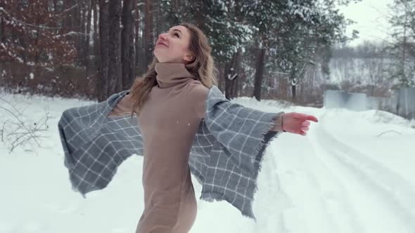 Happy Woman Wearing Scarf and Spinning on the Winter Forest Background