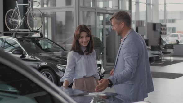 Man Gifting Car to Woman in Dealership