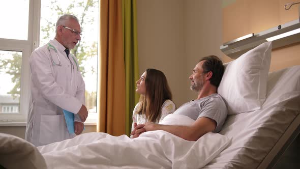Sick Man with Wife Listening To Doctor in Hospital