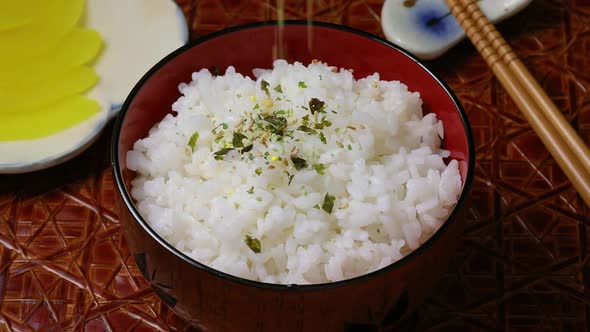  Sprinkling Wasabi furikake on top of Japanese white rice close up