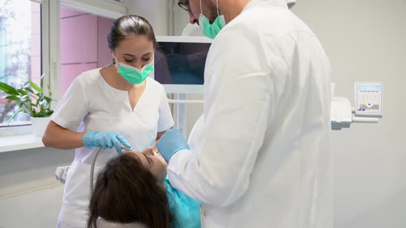 Dentist and his assistant examining the teeth of a patient