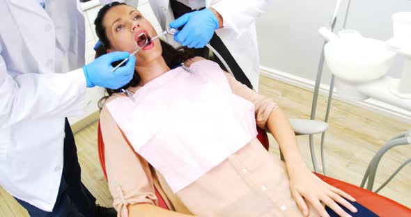 Dentists examining a female patient with tools