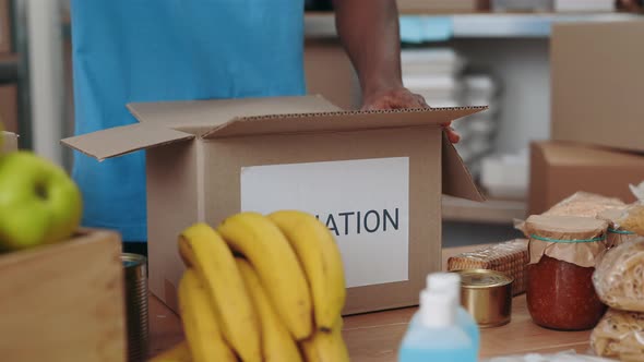 Close Up of Male Volunteer Filling Cardboard Donation Boxes