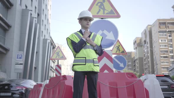 Portrait Cute Little Boy Wearing Business Suit and Safety Equipment and Constructor Helmet Standing