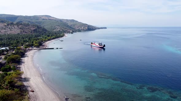 Rising aerial drone of passenger ferry leaving Atauro Island tropical island over stunning coral ree