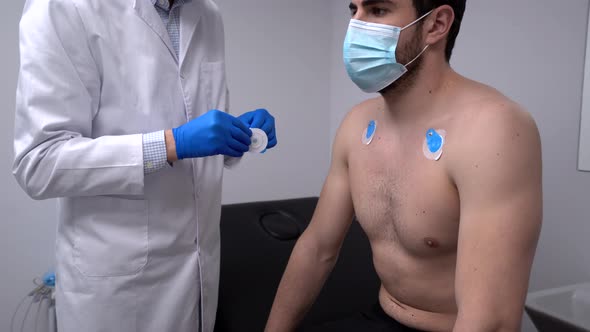 Crop doctor applying ECG electrodes on chest of patient