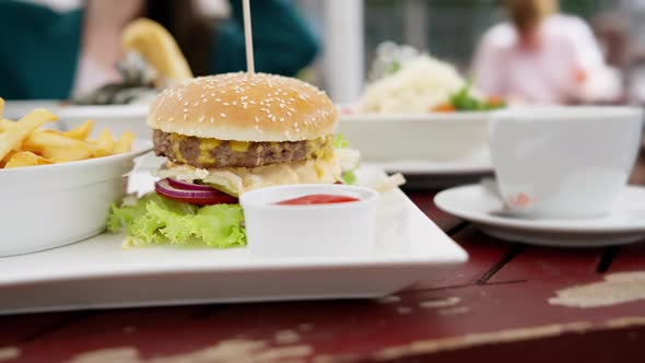 A fast food dinner consisting of a hamburger, french fries and a cup of sauce served on a tray.