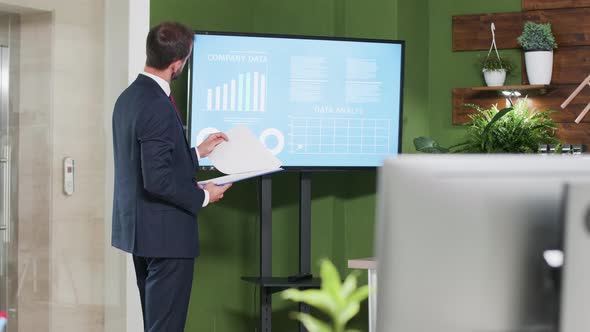 Caucasian Businessman Standing Near a Big Screen TV