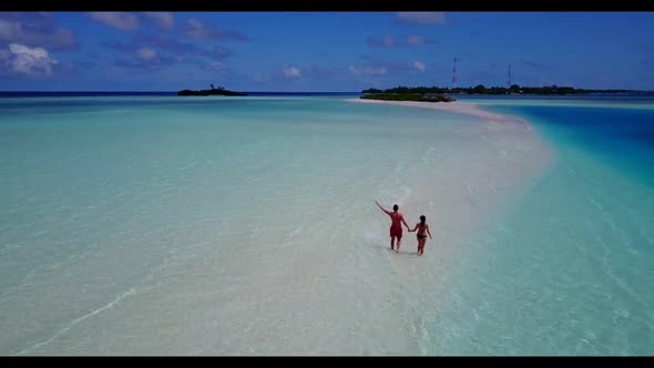 Man and woman tanning on beautiful lagoon beach time by shallow sea and white sandy background of th