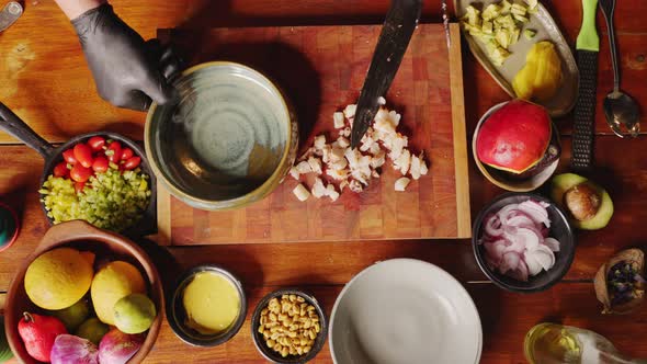 Preparation of ceviche salad - top down view of a chef transferring freshly cut seafood into a bowl,