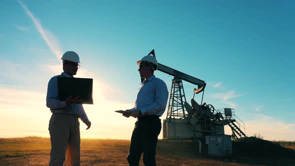 Two Oilmen Examining an Oilfield