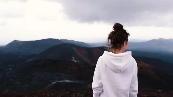 Happy Young Woman Tourist Stands on the Summit and Looks Out Over the Valley of Volcanoes Steaming