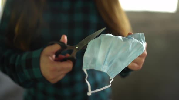 After Quarantine. Hands of Girl Is Using Scissors To Cut or Destroy Medical Protective Mask That Has