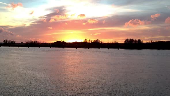 Silhouetted river shore against a beautiful red-gold sunset.