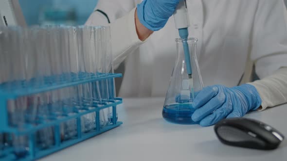 Biologist Using Micro Pipette to Mix Substance in Beaker and Test Tube