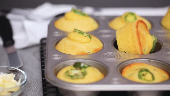 Step by step. Taking out freshly baked spicy jalapeno cornbread muffins from metal muffin pan.