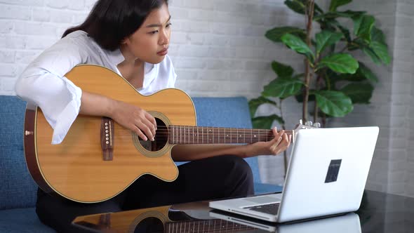 Woman Practicing and Learning How to Play Guitar on Laptop