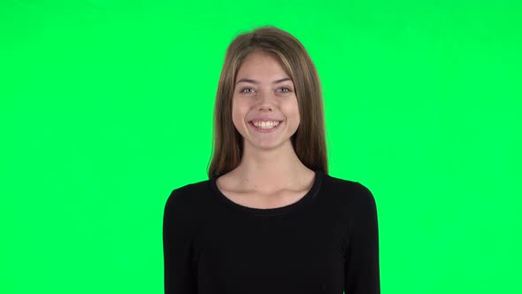 Young Woman Smiling While Looking at Camera and Rejoicing. Green Screen