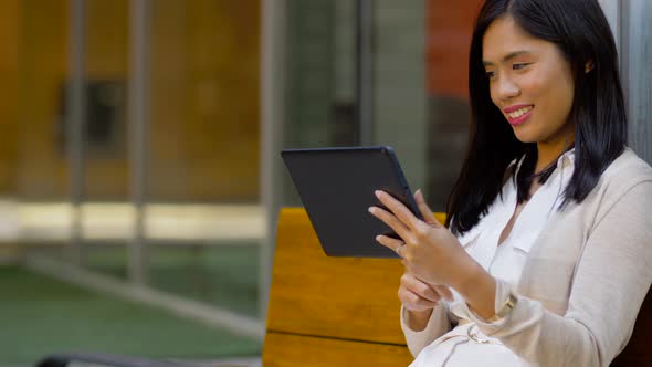 Asian Woman with Tablet Computer Sitting on Bench