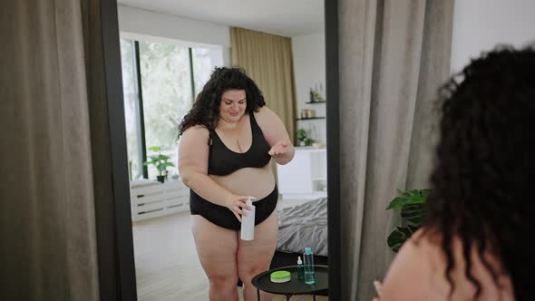 Young Overweight Woman Puts Cream on Arm Against Mirror