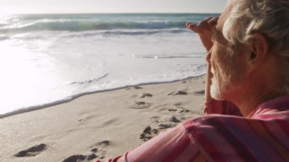 Senior man sitting looking away at the beach