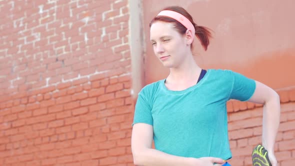 A young woman stretching before working out in urban environment.