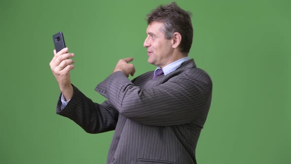 Mature Handsome Businessman Against Green Background